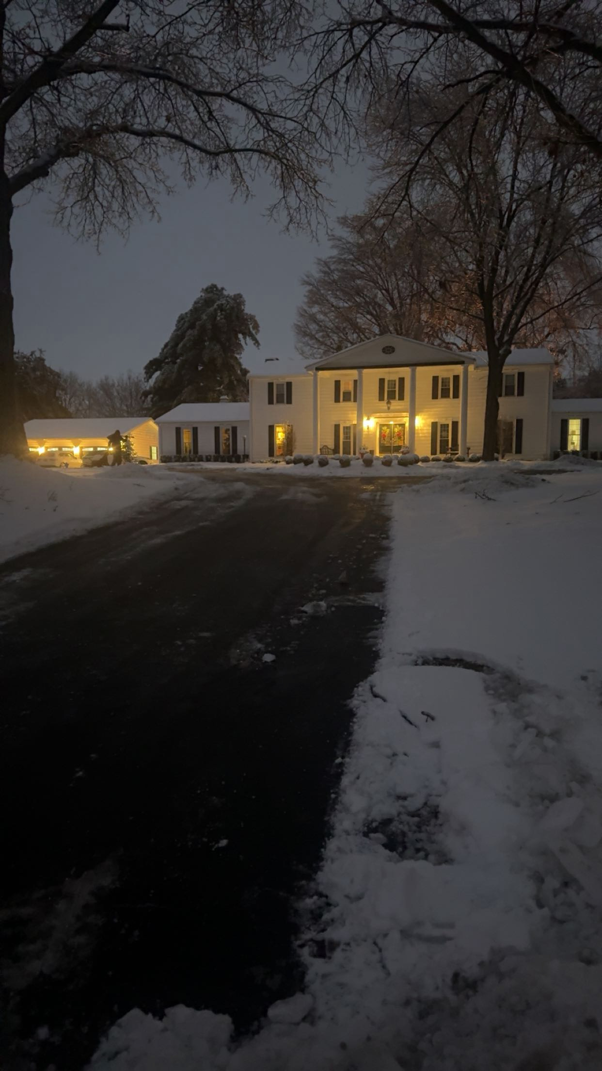 Cleared driveway in front of a white home at dusk