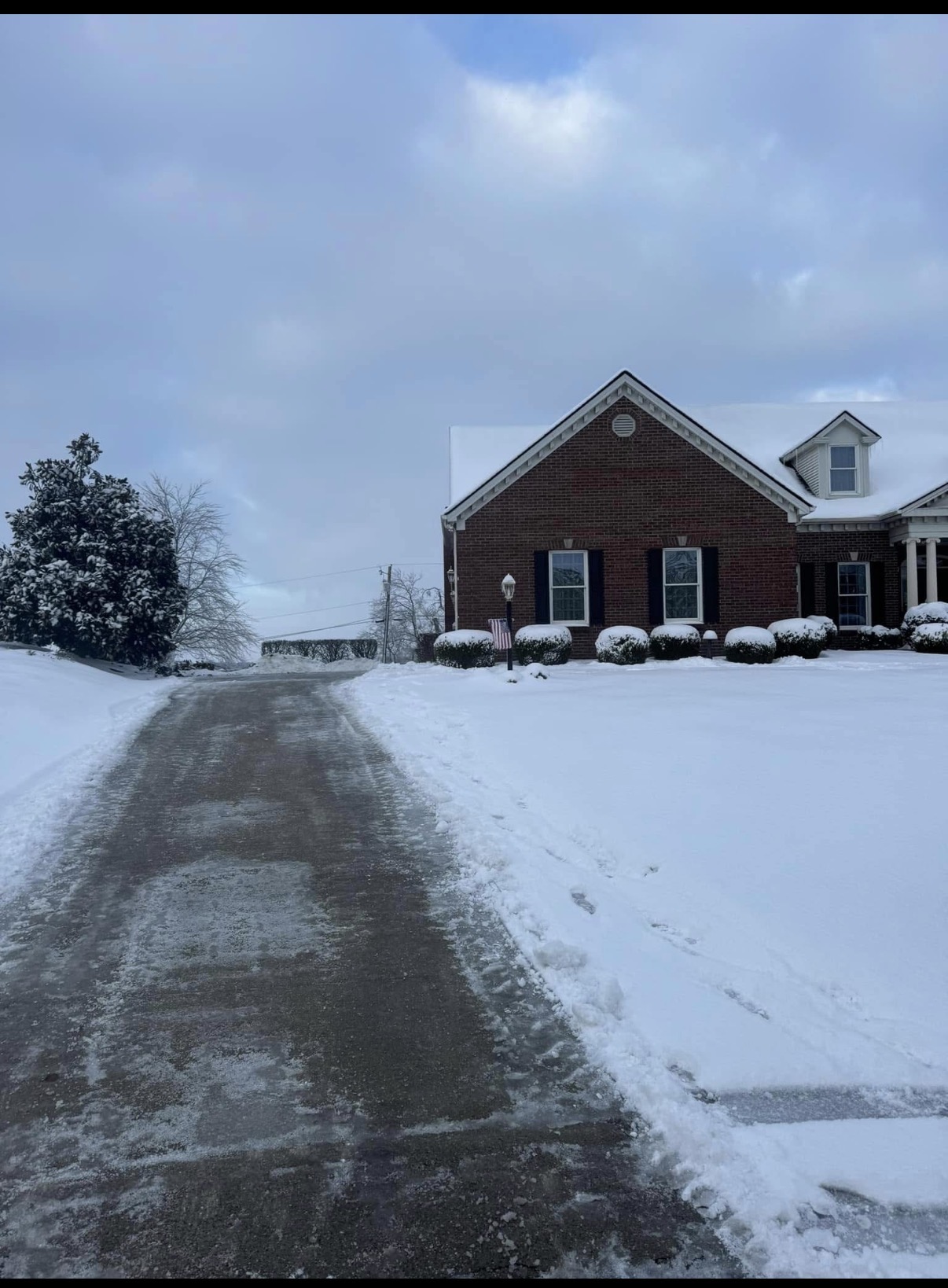 Cleared driveway beside a brick home after snowfall