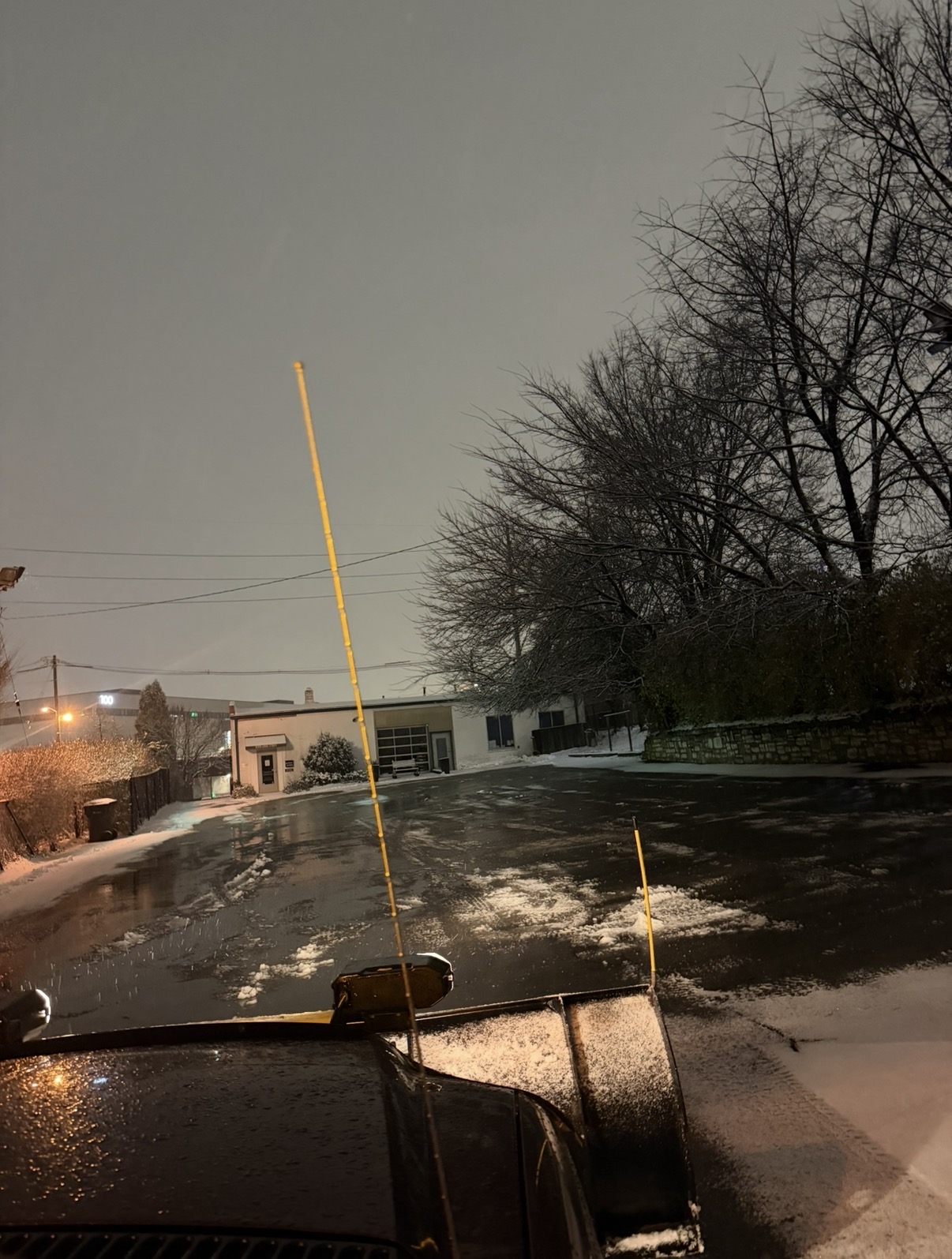 Snowplow clearing a paved property at night